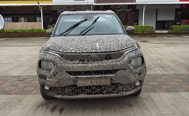 The test mule of the Tata HBX appears to be a lower-spec variant featuring halogen headlamps with LED DRLs integrated on the stripe above and circular halogen fog lamps.