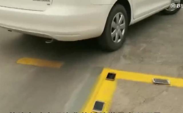 This driving school in China teaches its students to reverse their vehicles into a parking spot by having them place their smartphones on the ground on top of the yellow line marking the space.